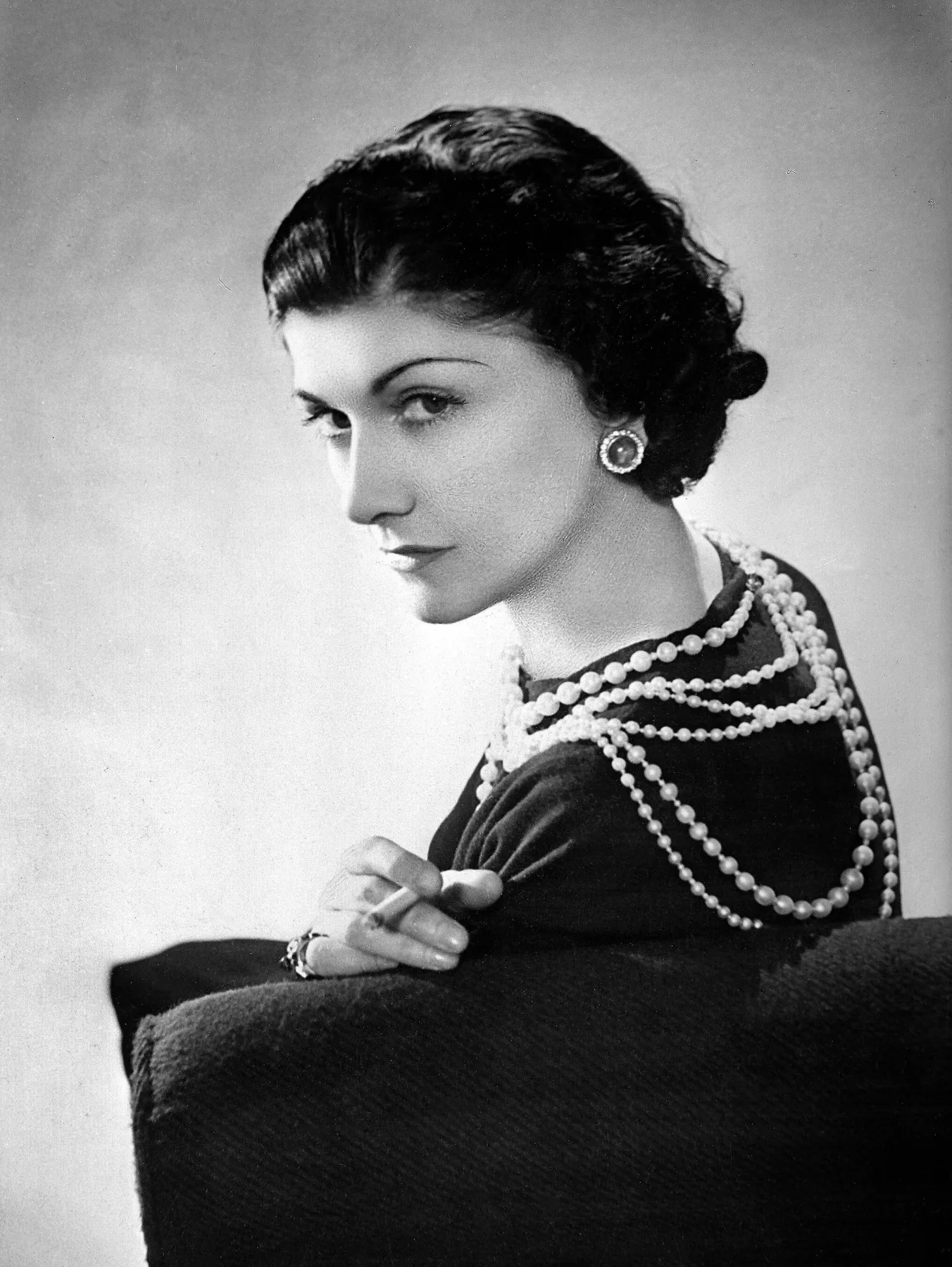 Coco Chanel in black with strands of pearl necklace