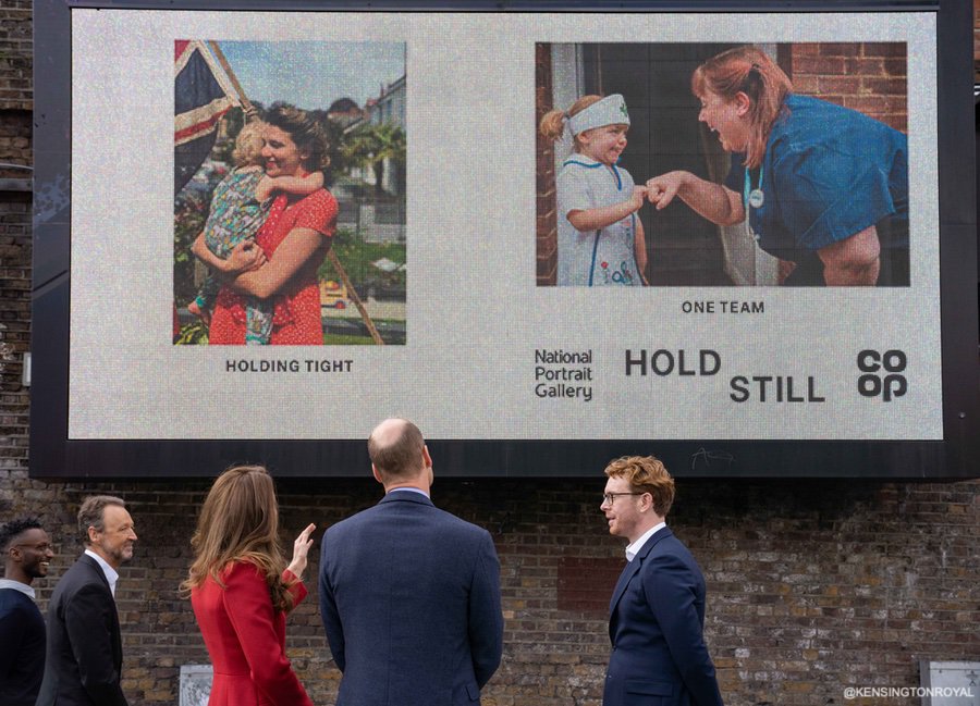 Kate Middleton Duchess of Cambridge custom made/bespoke Alexander McQueen red double breast full length coat with peak lapel for Hold Still photography project at Waterloo Station in London 