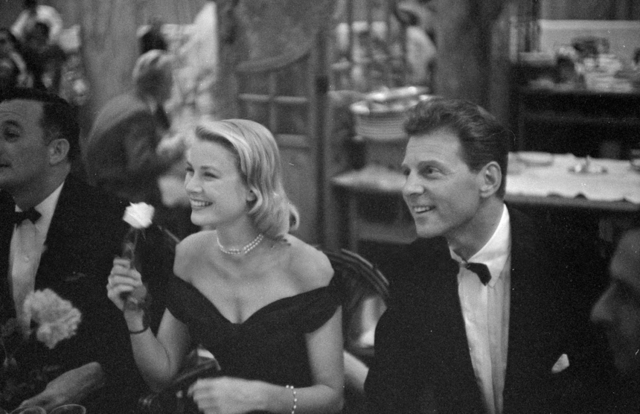 Elegant style icon wardrobe essentials: Grace Kelly in black dress, with Jean-Pierre Aumont. Cannes Film Festival 1955.