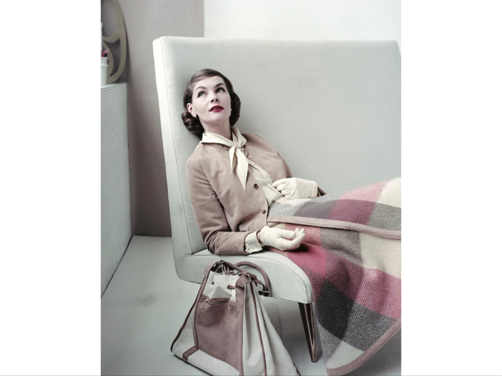 Model sitting in chair wearing plaid skirt, suede jacket,blouse and gloves by Glen of Michigan, Glamour August 1955© Frances McLaughlin-Gill