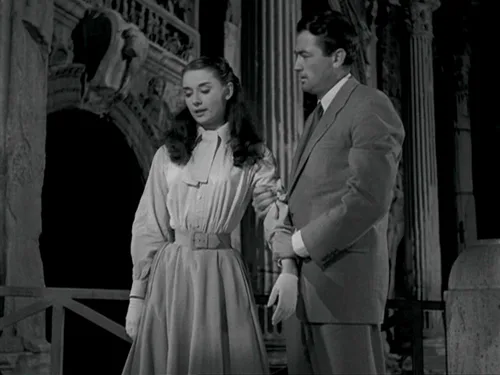 Audrey Hepburn in a white shirt with buttoned sleeves and Gregory Peck at a doorway, Roman Holiday (film, 1953)