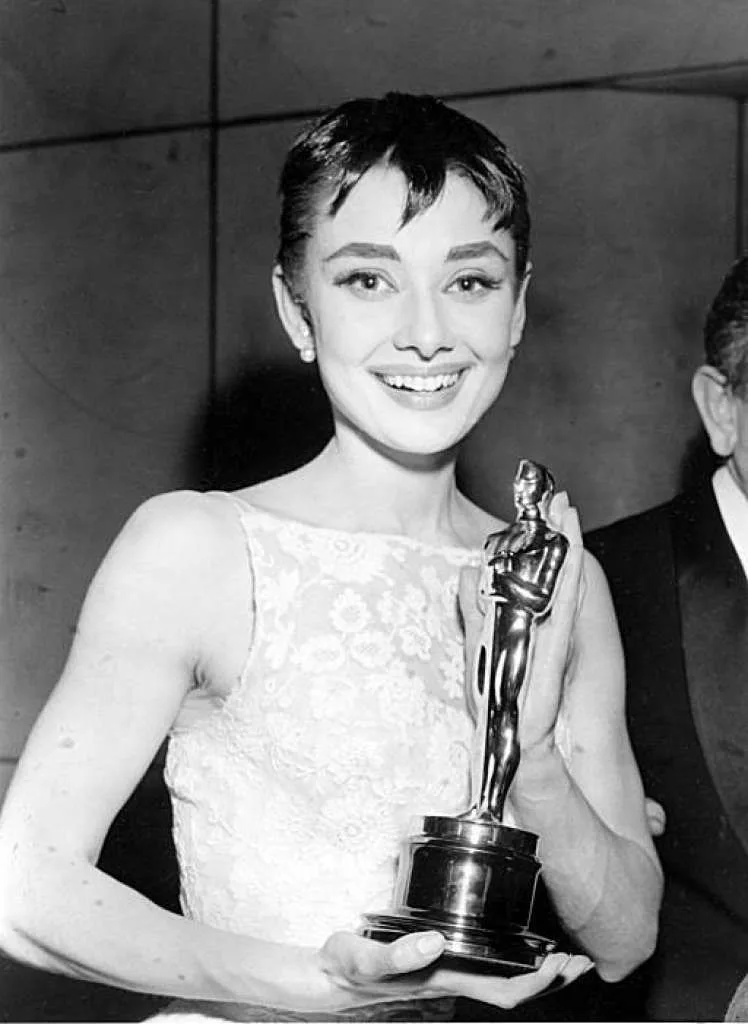 Audrey Hepburn smiling with her Oscar in the white lace dress, 1954
