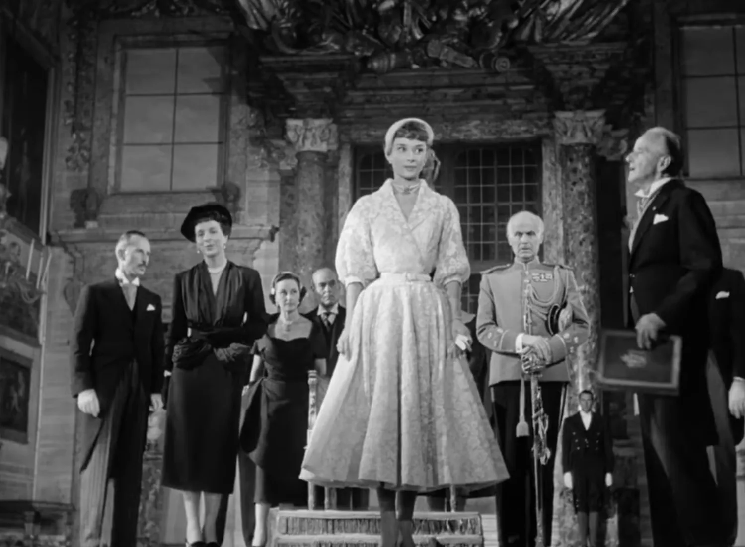 Audrey Hepburn standing in an ivory lace dress at the press conference, Roman Holiday (film, 1953)