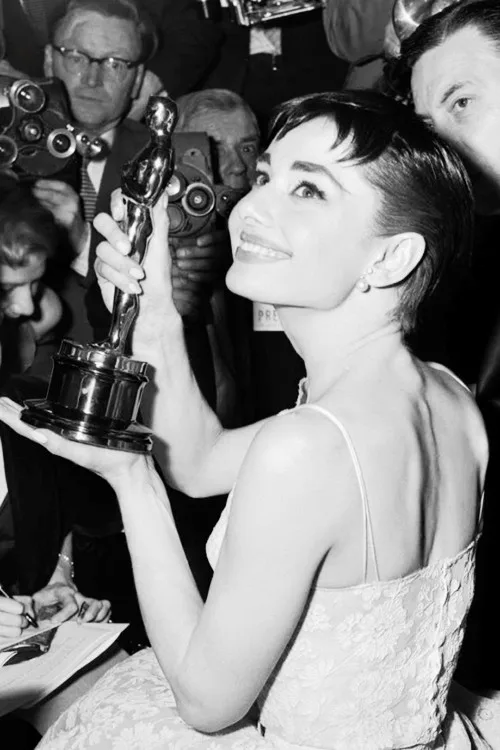 Audrey Hepburn holding her Oscar among photographers, 1954