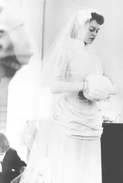 Brigitte Bardot in her wedding dress holding a white muff, 1952