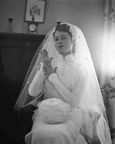 Brigitte Bardot in her wedding dress with her white muff on her knees, 1952