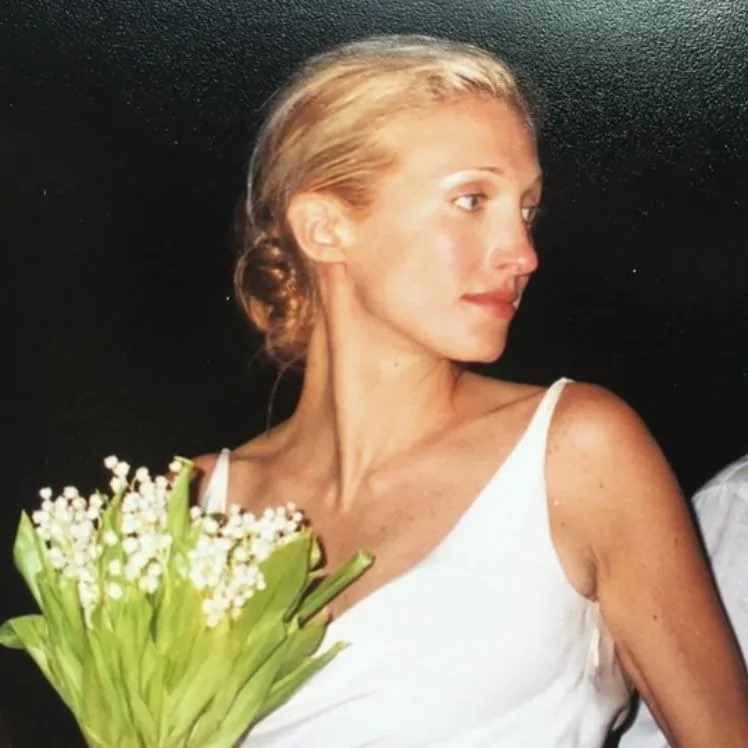 Close view of Carolyn Bessette with her lily of the valley bouquet and the thin straps of her slip dress, 1996