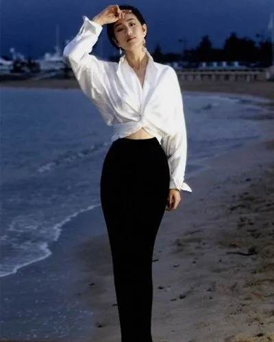 Gong Li in a white knotted shirt and black column skirt by the water at Cannes, 1993