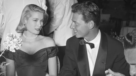 Grace Kelly in black dress, with Jean-Pierre Aumont. Cannes Film Festival, photo by Edward Quinn, 1955.