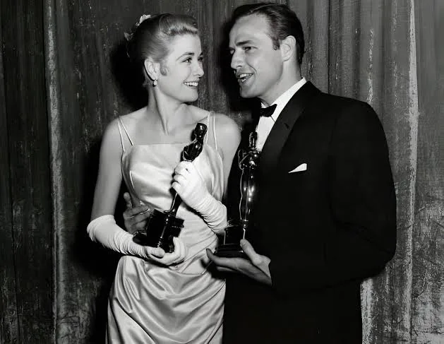 Grace Kelly in her satin gown and white gloves with Marlon Brando, black and white photo, 1955
