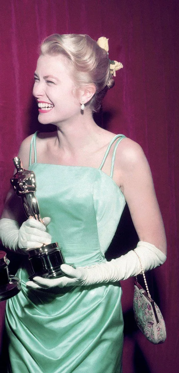 Grace Kelly in her ice-blue silk satin gown and long white gloves, holding her Oscar, 1955