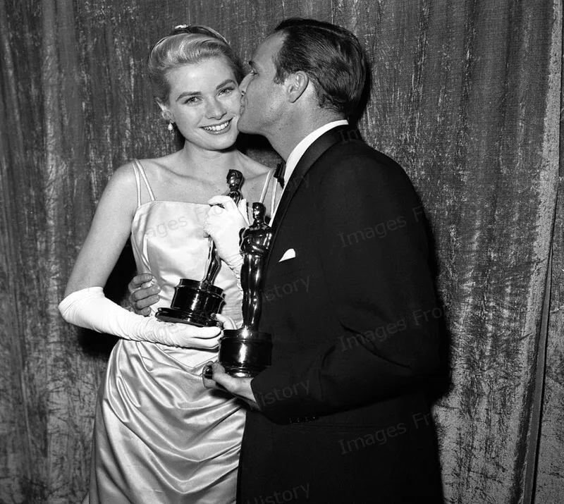Grace Kelly in her satin gown with Marlon Brando, both holding their Oscars, black and white photo, 1955