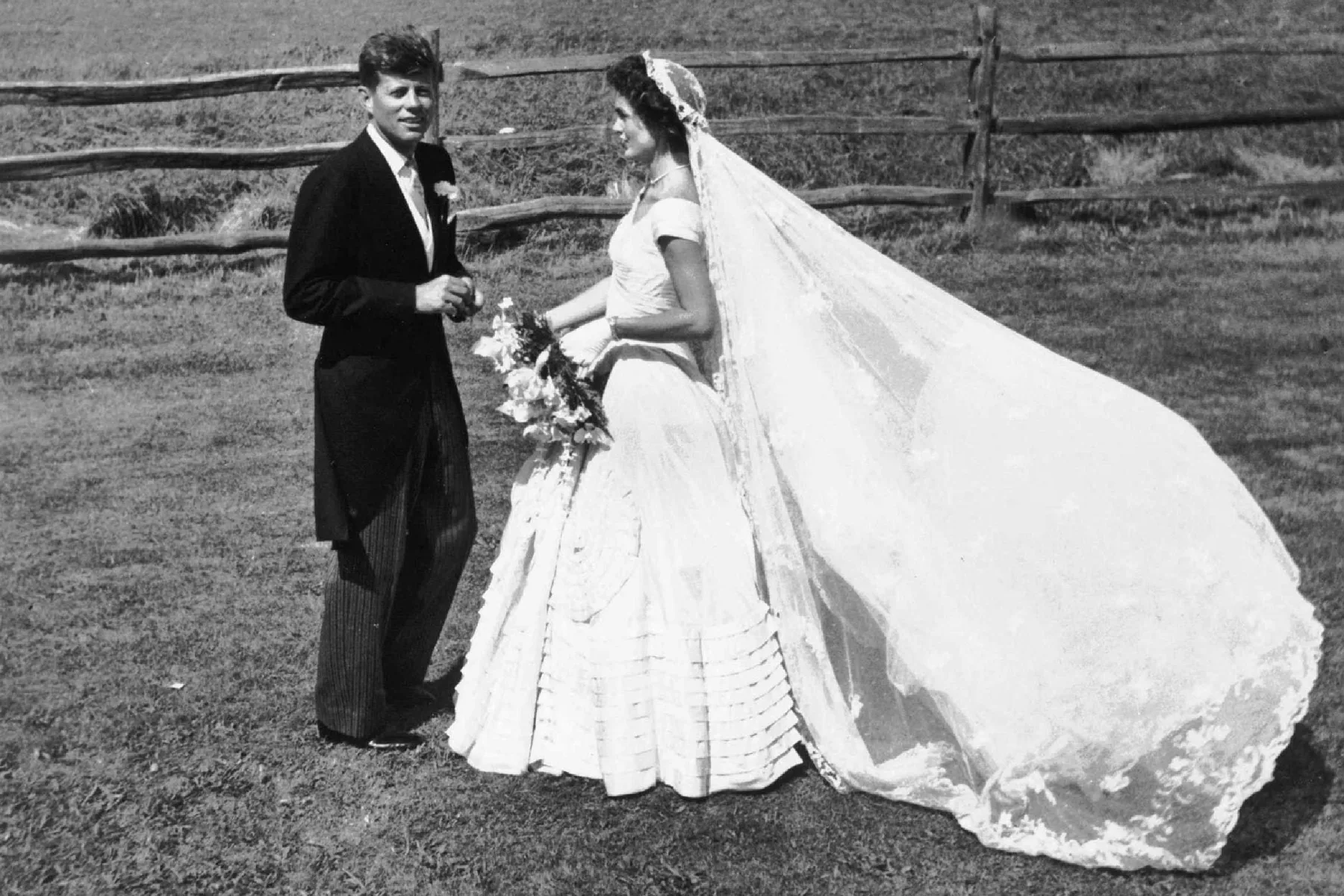Jacqueline Bouvier and John F. Kennedy on the lawn, her lace veil blowing in the wind, 1953