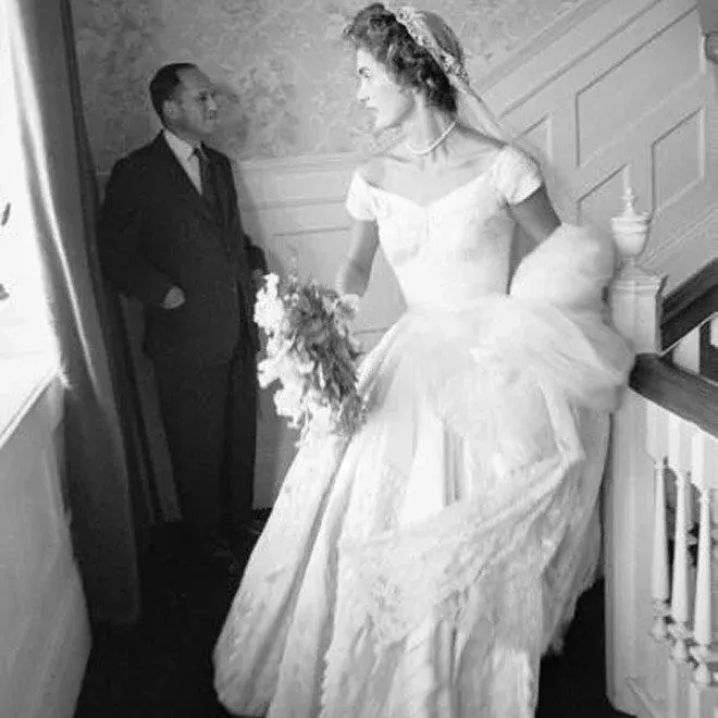 Jacqueline Bouvier in her wedding dress and lace veil indoors, 1953