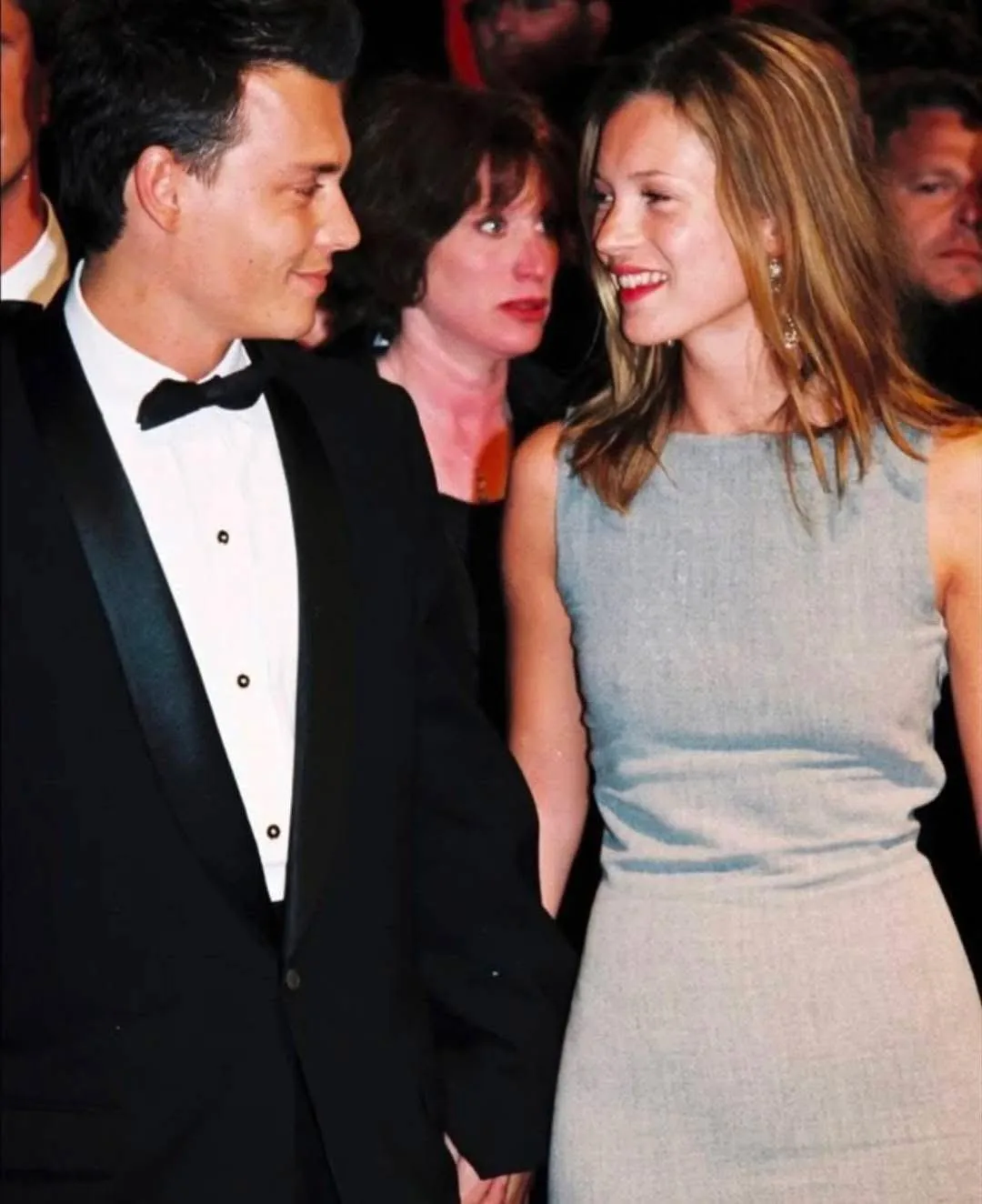 Kate Moss in her sleeveless grey dress with a boat neckline, smiling at Johnny Depp, Cannes, 1997