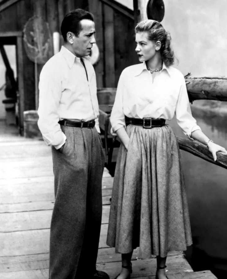 Lauren Bacall in a white shirt and full skirt with Humphrey Bogart on the hotel stairs, Key Largo (film, 1948)