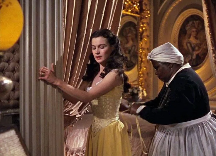 Vivien Leigh as Scarlet O’Hara in film Gone with the Wind(1939), wearing corset with the help of her maid